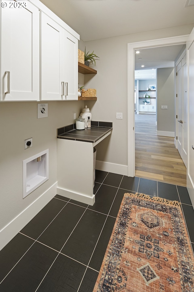 laundry room with cabinets, electric dryer hookup, and dark hardwood / wood-style floors