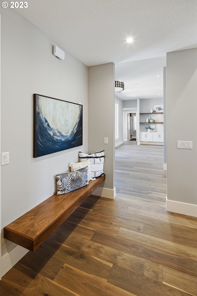 hall with a textured ceiling and light hardwood / wood-style floors