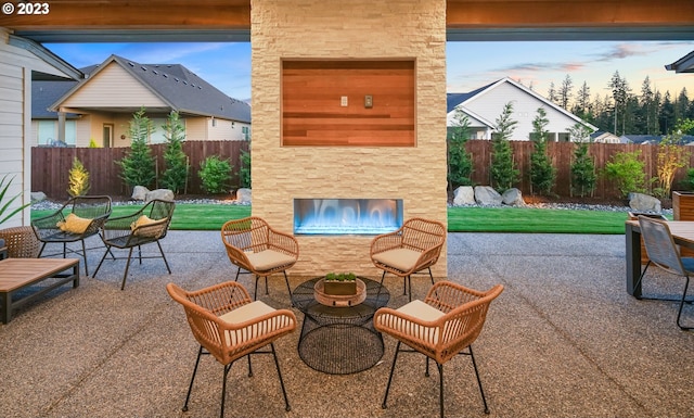 patio terrace at dusk featuring a lawn and an outdoor stone fireplace