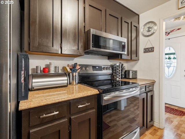 kitchen featuring light stone countertops, stainless steel appliances, light hardwood / wood-style floors, and dark brown cabinetry