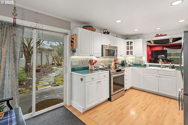 11215 NE 359th St, La Center, WA 98629 - kitchen with appliances with stainless steel finishes, a sink, light wood-style floors, tasteful backsplash, and ornamental molding