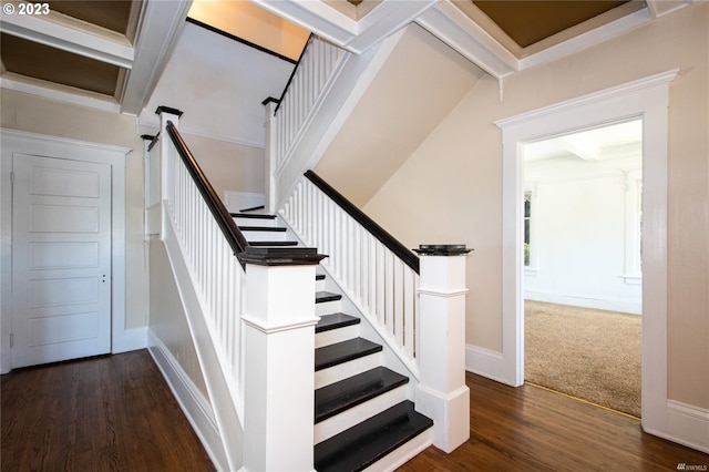 staircase with beam ceiling and dark colored carpet