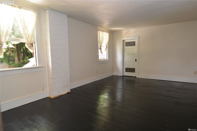 empty room with brick wall and dark wood-type flooring