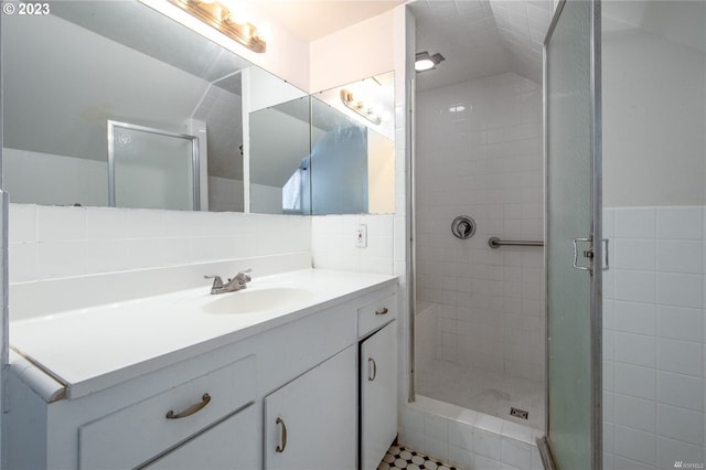 bathroom featuring tile flooring, large vanity, a shower with shower door, and tile walls