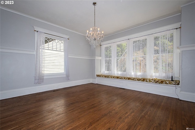 empty room with dark hardwood / wood-style flooring, a notable chandelier, ornamental molding, and a healthy amount of sunlight