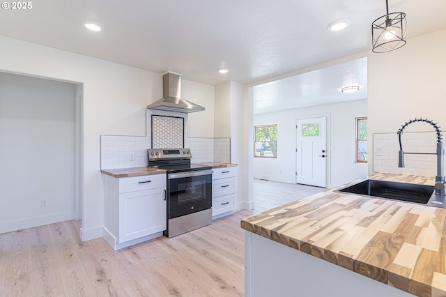 2604 15th St, Baker City, OR 97814 - kitchen with wood counters, stainless steel range with electric cooktop, wall chimney exhaust hood, a sink, and light wood-style flooring
