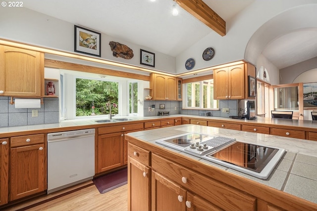 kitchen featuring vaulted ceiling with beams, light hardwood / wood-style flooring, backsplash, sink, and white dishwasher