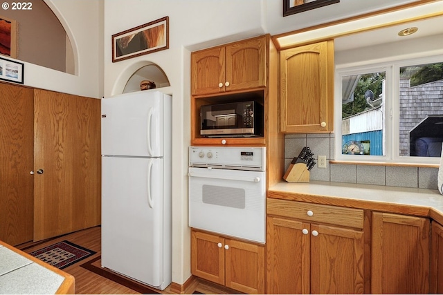 kitchen featuring white appliances, tasteful backsplash, and dark hardwood / wood-style flooring