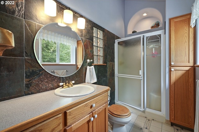 bathroom with tile walls, toilet, a shower with shower door, tile floors, and large vanity