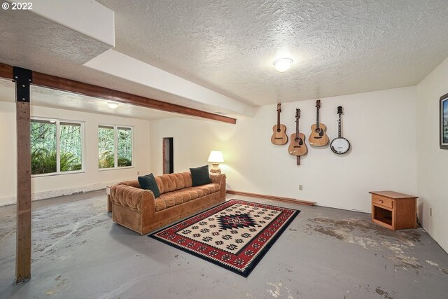 living room featuring concrete flooring, beam ceiling, and a textured ceiling