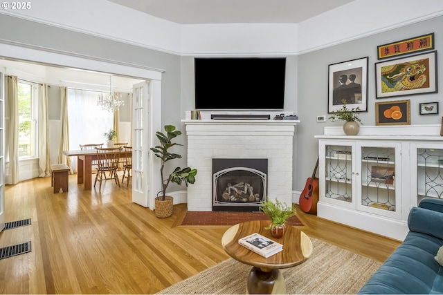 2147 NE 14th Ave, Portland, OR 97212 - living area with a chandelier, wood finished floors, and a brick fireplace