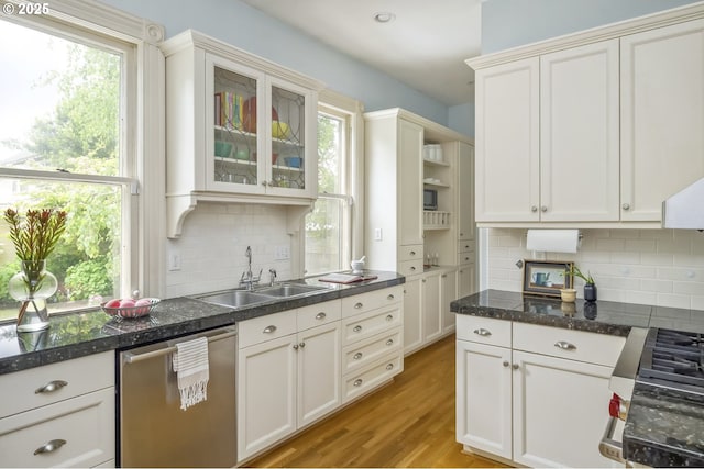 2147 NE 14th Ave, Portland, OR 97212 - kitchen featuring stainless steel dishwasher, a sink, decorative backsplash, light wood-style floors, and glass insert cabinets