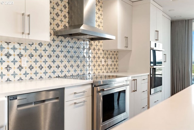 kitchen with white cabinetry, tasteful backsplash, stainless steel appliances, and wall chimney exhaust hood