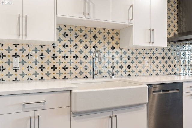 kitchen featuring wall chimney range hood, sink, white cabinetry, and stainless steel dishwasher