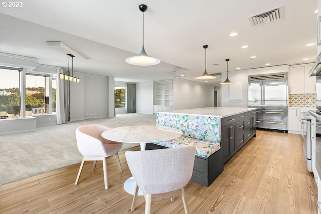 interior space with white cabinets, a kitchen island, light wood-type flooring, and pendant lighting