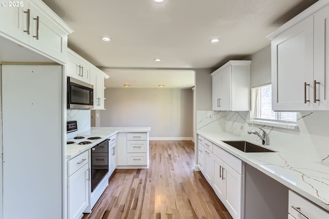 kitchen featuring white cabinetry, sink, light stone counters, and tasteful backsplash