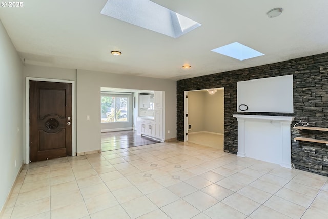 unfurnished living room featuring light tile patterned flooring and a skylight