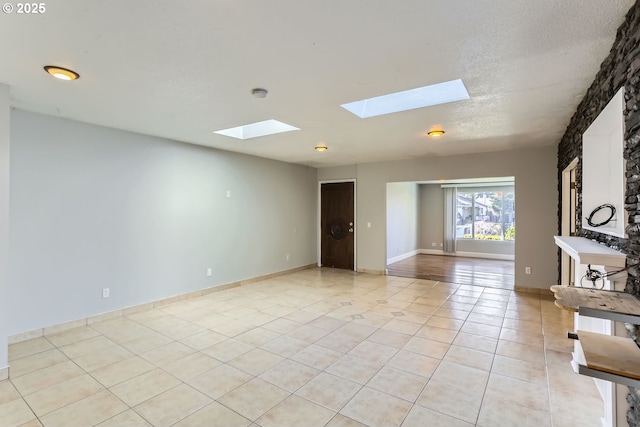 tiled empty room with a skylight and a textured ceiling