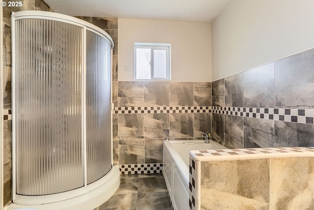 bathroom featuring shower with separate bathtub and tile walls