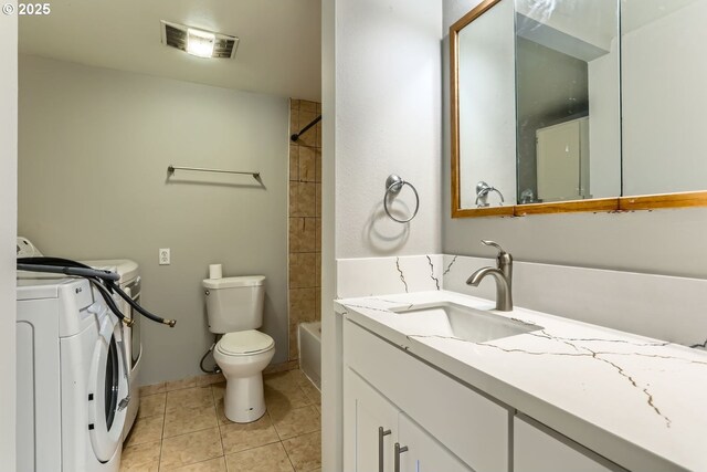 full bathroom featuring tile patterned flooring, washing machine and dryer, vanity, toilet, and tiled shower / bath