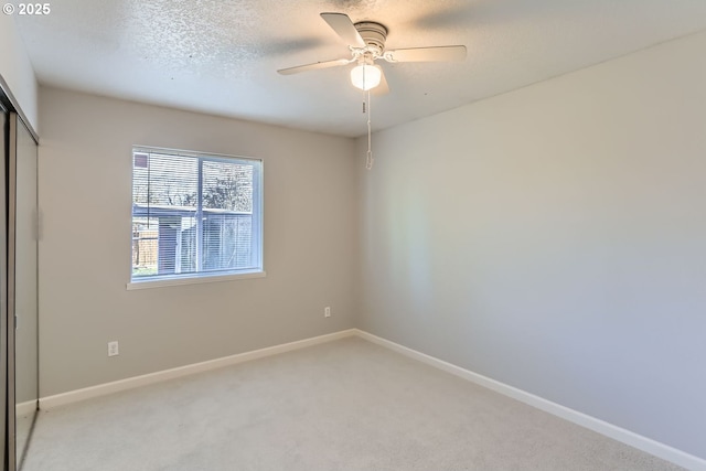 unfurnished bedroom featuring a textured ceiling, light colored carpet, a closet, and ceiling fan