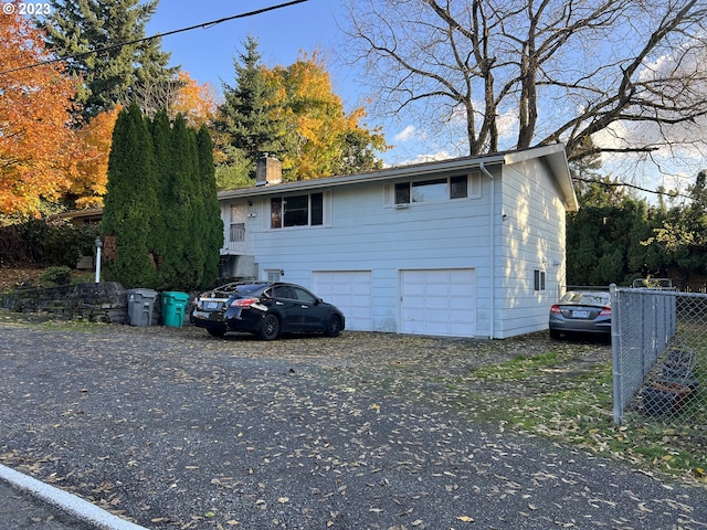 view of front of property with fence, a chimney, an attached garage, and aphalt driveway