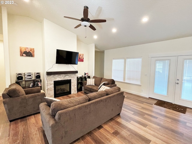 living room featuring french doors, vaulted ceiling, ceiling fan, a fireplace, and wood-type flooring