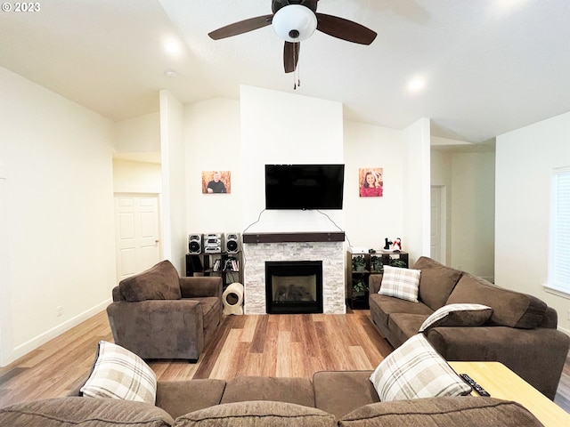 living room with ceiling fan, a fireplace, vaulted ceiling, and light hardwood / wood-style flooring