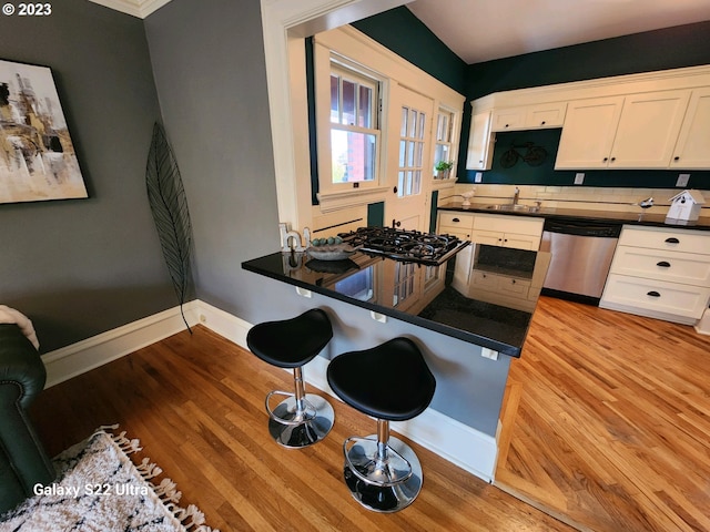 kitchen with light hardwood / wood-style floors, white cabinets, tasteful backsplash, and stainless steel dishwasher