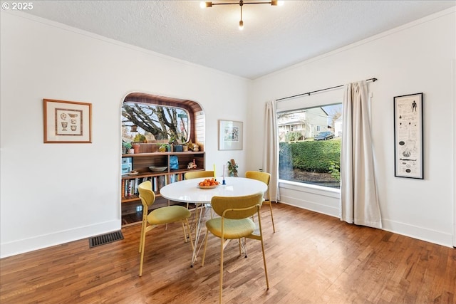 dining room featuring ornamental molding, hardwood / wood-style floors, and a textured ceiling