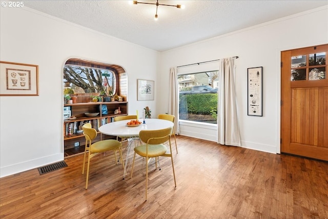 dining room with ornamental molding, hardwood / wood-style floors, and a textured ceiling