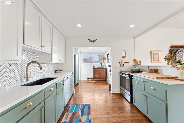 kitchen with stainless steel electric stove, white cabinetry, sink, decorative backsplash, and light hardwood / wood-style flooring