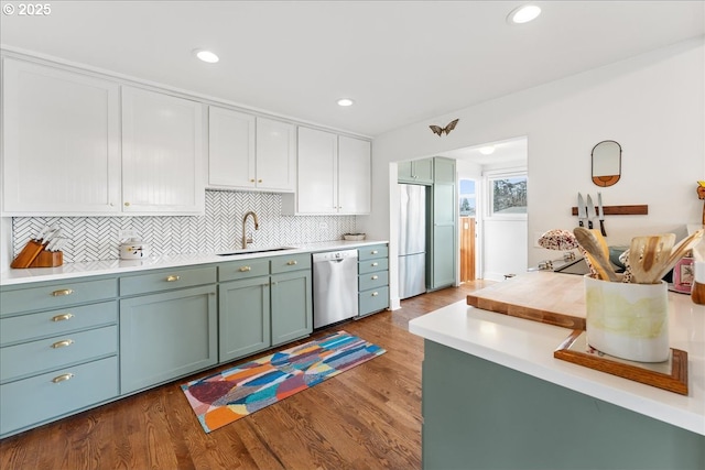 kitchen with hardwood / wood-style flooring, appliances with stainless steel finishes, sink, and decorative backsplash