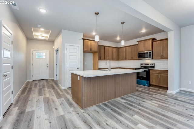 kitchen with a kitchen island with sink, stainless steel appliances, light wood-type flooring, and sink