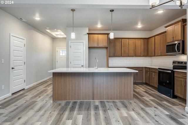 kitchen with electric stove, a kitchen island with sink, light wood-type flooring, and sink