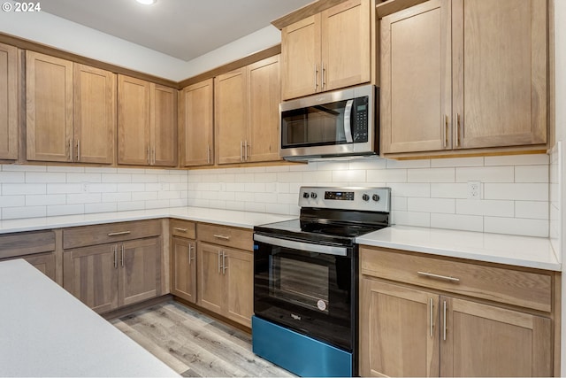 kitchen featuring light wood-type flooring, backsplash, and appliances with stainless steel finishes