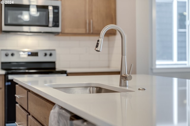 kitchen featuring pendant lighting, backsplash, sink, and range with electric cooktop