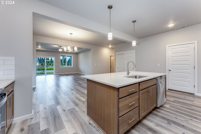 kitchen featuring a kitchen island with sink, light hardwood / wood-style floors, decorative light fixtures, and sink