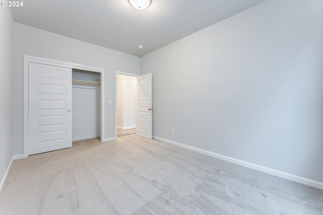 unfurnished bedroom featuring light carpet and a closet