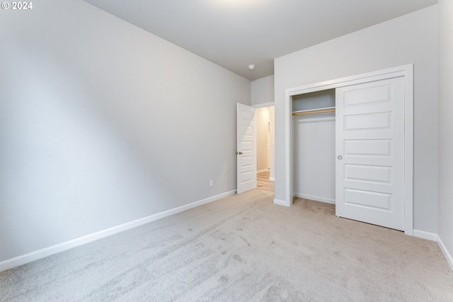 unfurnished bedroom with light carpet and a closet