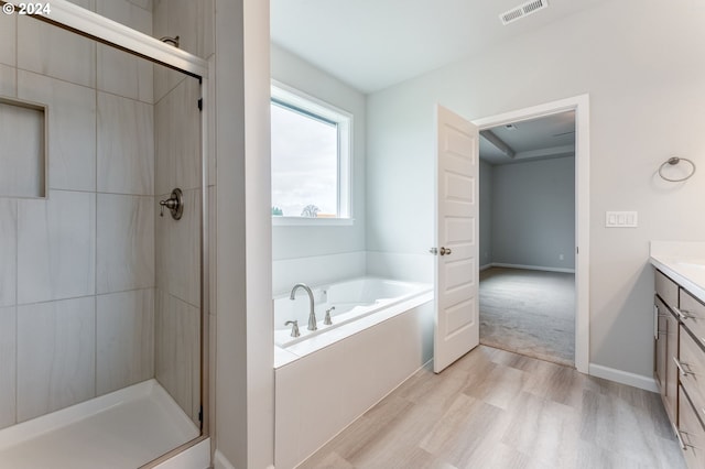 bathroom with wood-type flooring, vanity, and plus walk in shower