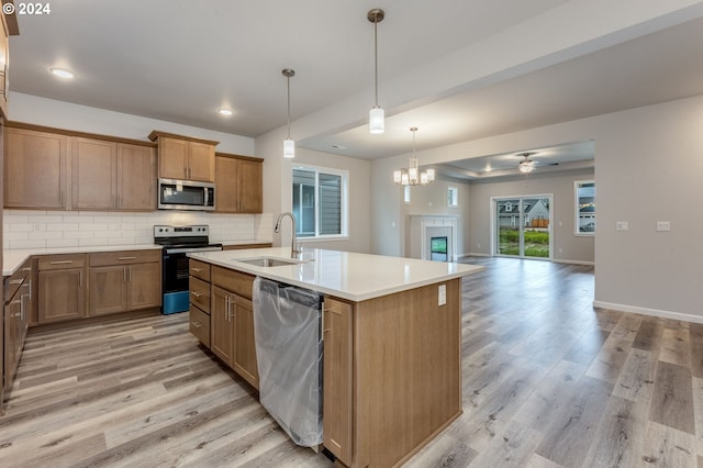 kitchen featuring appliances with stainless steel finishes, sink, light hardwood / wood-style flooring, and an island with sink