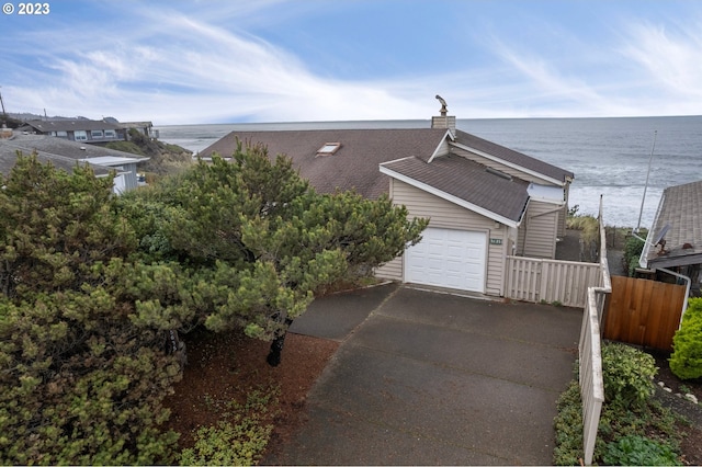 view of front of home with a water view, fence, and aphalt driveway