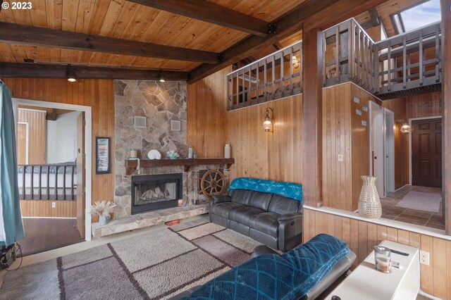 living room with beam ceiling, hardwood / wood-style floors, wooden walls, a fireplace, and wood ceiling