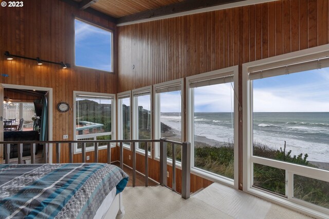 unfurnished sunroom featuring vaulted ceiling with beams, a water view, and plenty of natural light