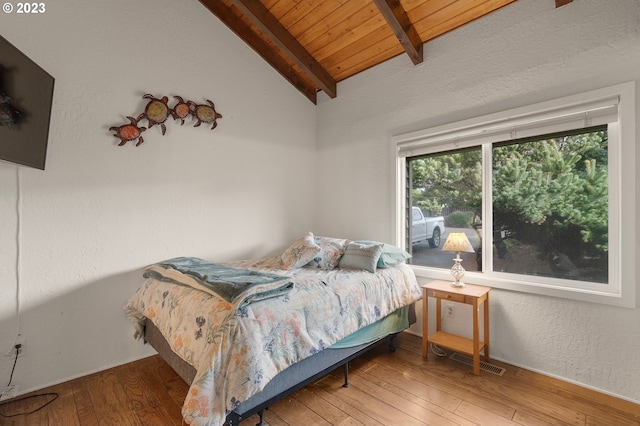 bedroom featuring visible vents, a textured wall, wood ceiling, hardwood / wood-style floors, and vaulted ceiling with beams