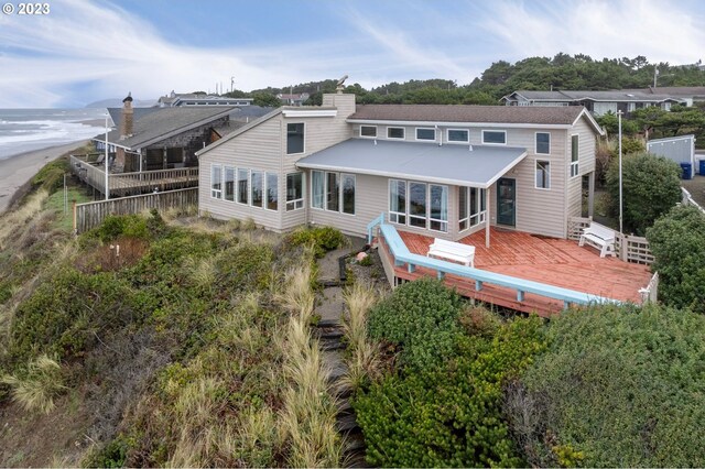 wooden deck featuring a water view and a view of the beach