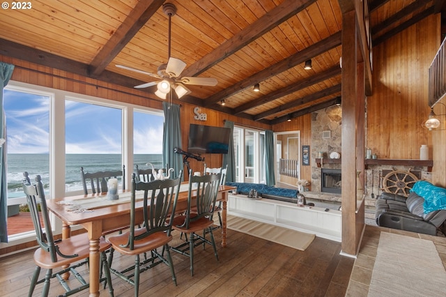 dining area with a stone fireplace, hardwood / wood-style floors, wood walls, and wood ceiling