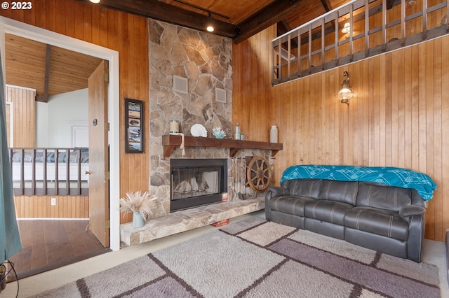 living area featuring wood ceiling, beamed ceiling, wooden walls, and a stone fireplace