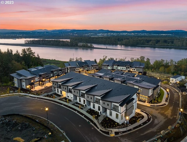 aerial view at dusk featuring a water view